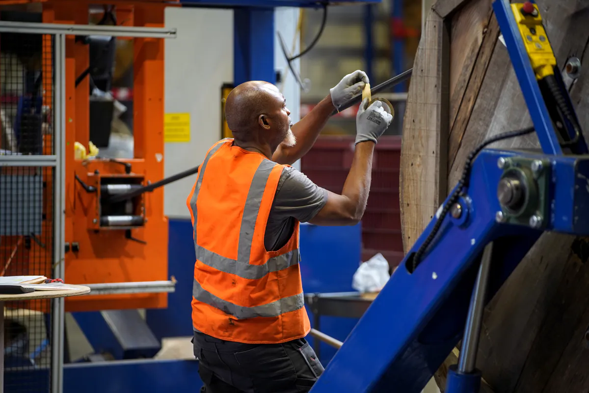 Opérateur REMATEC en gilet haute visibilité contrôlant la qualité d'un câble en atelier