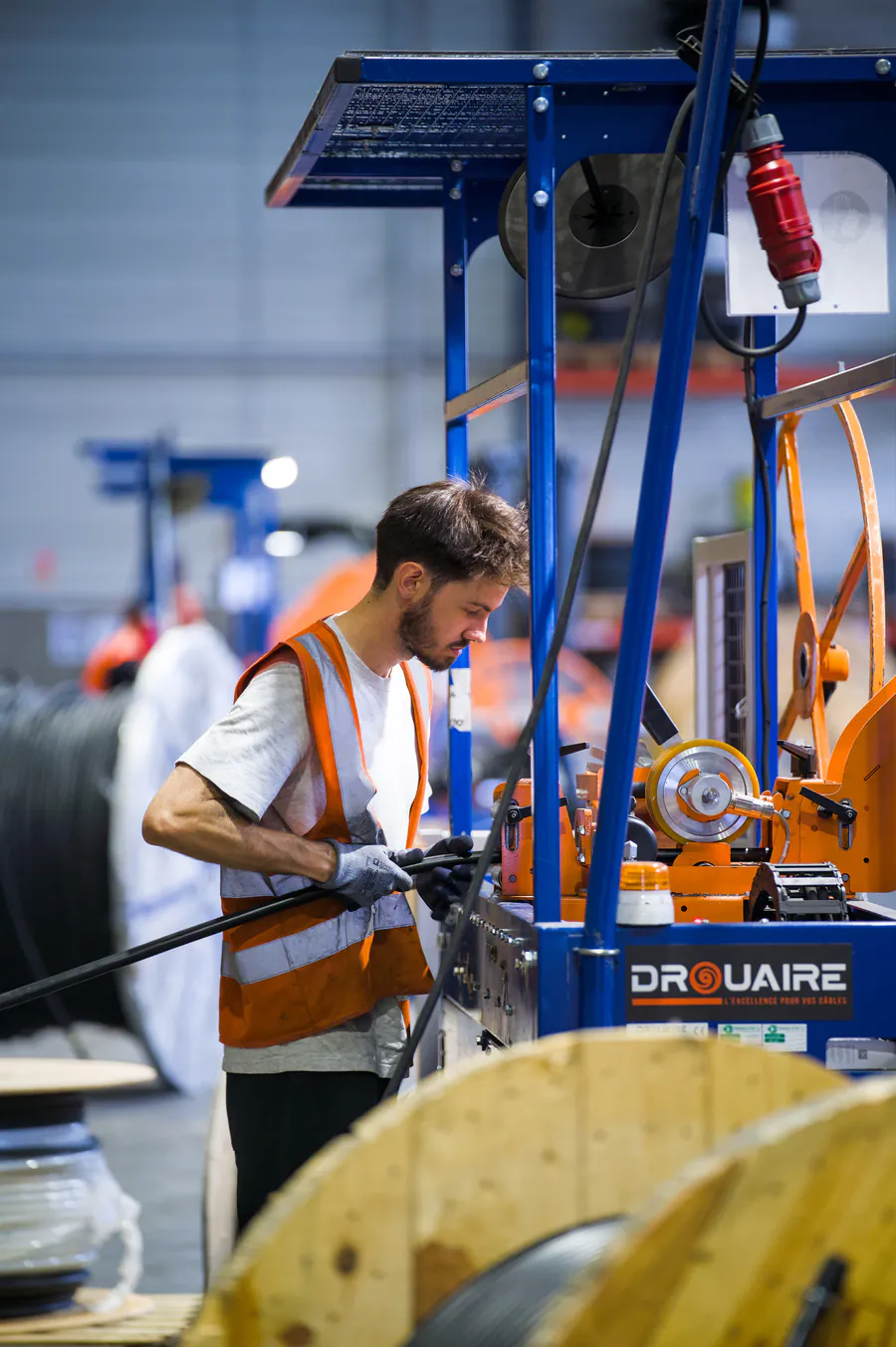 Technicien REMATEC en gilet orange travaillant sur un touret de câble en atelier