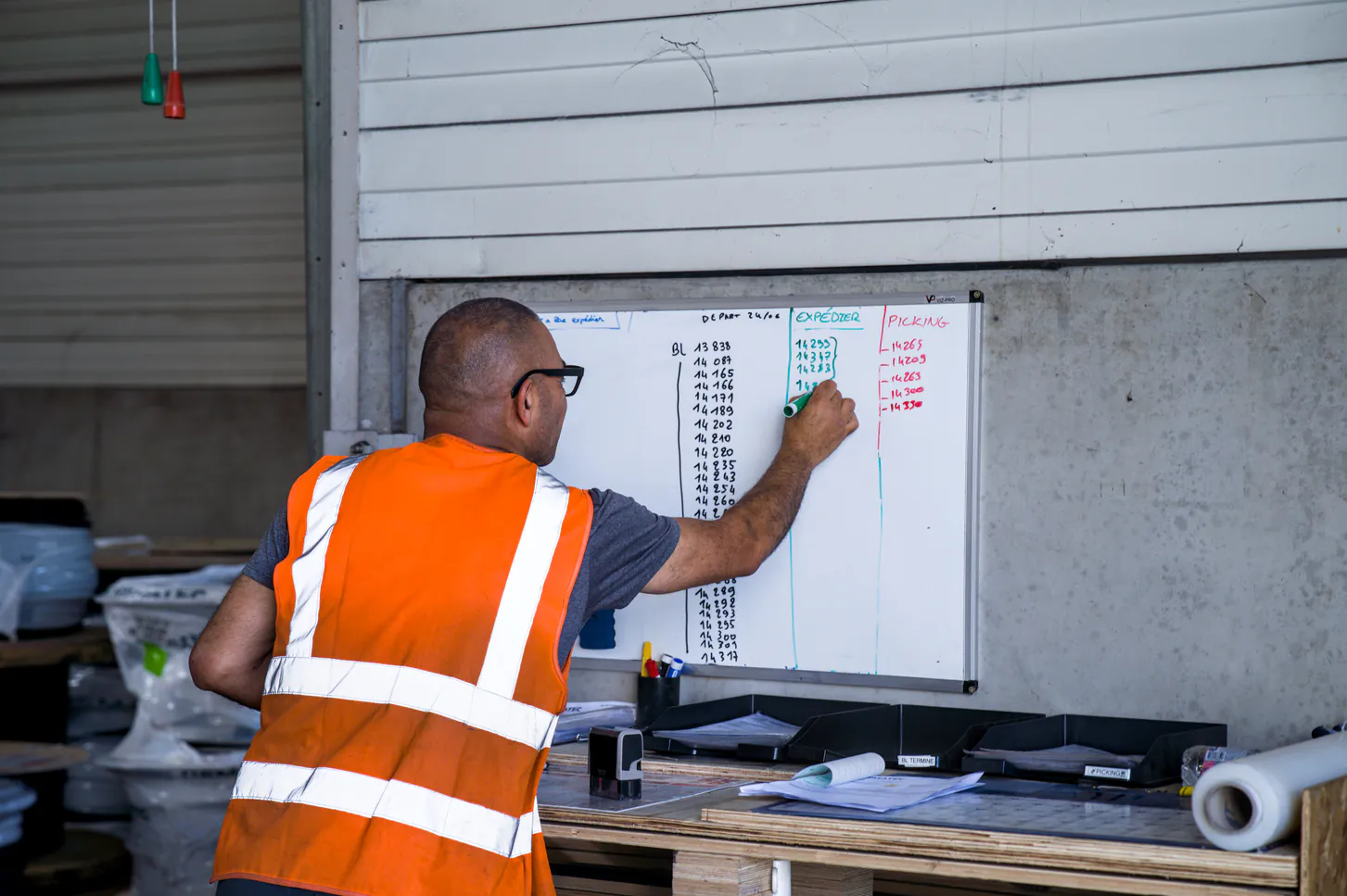Technicien Rematec écrivant les informations d'expédition sur un tableau blanc dans l'entrepôt