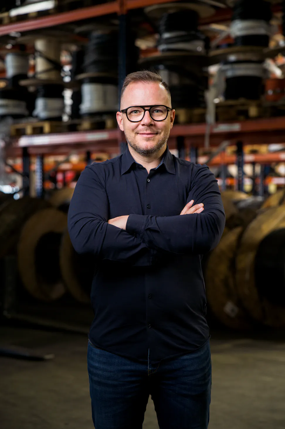 Pascal Rea, dirigeant de Rematec, bras croisés dans l'entrepôt devant des tourets de câble
